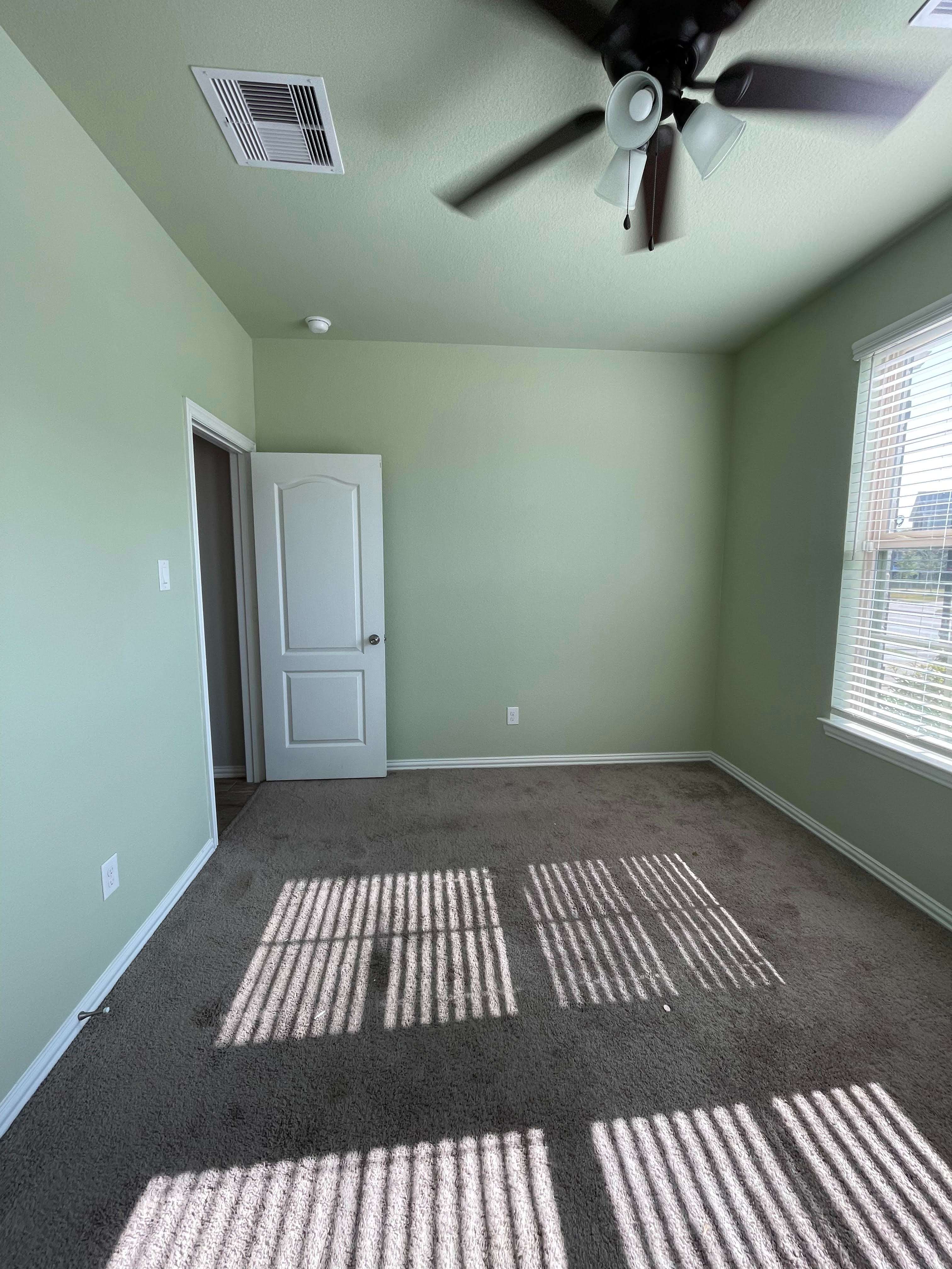 An empty room with a ceiling fan and a door